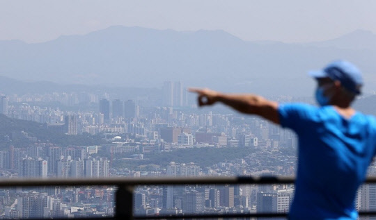 한 시민이 도심 아파트 밀집 지역을 가리키고 있다. <연합뉴스>
